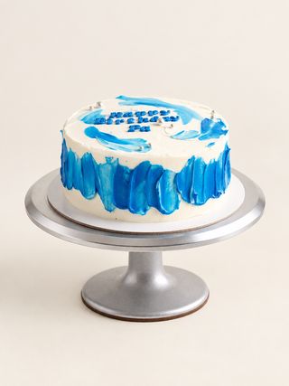 Round white cake decorated with painterly blue buttercream brushstrokes