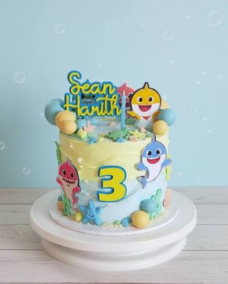 Colorful third birthday cake with smiling shark decorations and an underwater scene