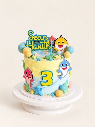 Colorful third birthday cake with smiling shark decorations and an underwater scene