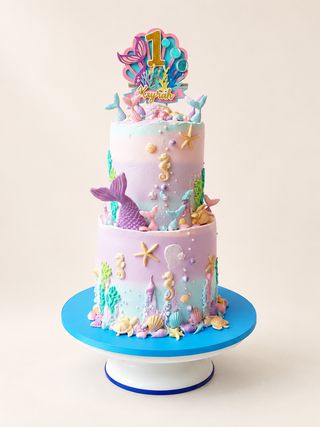 Two-tier pastel mermaid birthday cake with seashells, seahorses, coral, and a number one topper