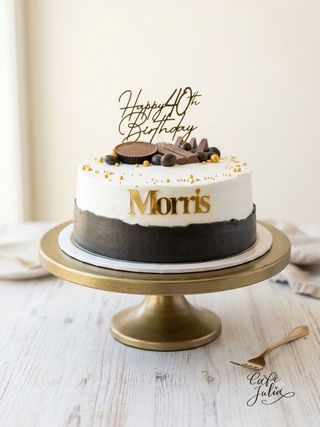 Black and white fortieth birthday cake with gold lettering and chocolate decorations