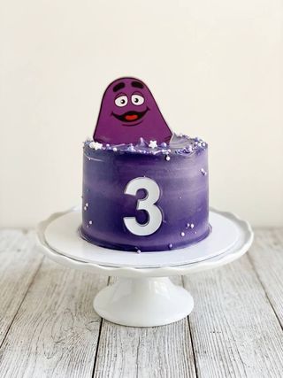 Purple third birthday cake with a playful purple character topper and silver number three