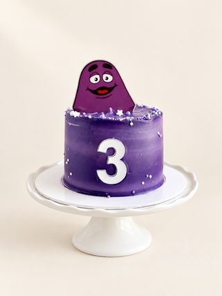 Purple third birthday cake with a playful purple character topper and silver number three